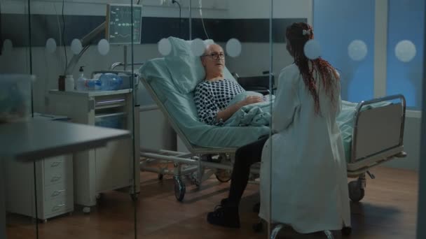 Médico afroamericano hablando con paciente enfermo en sala de hospital — Vídeo de stock