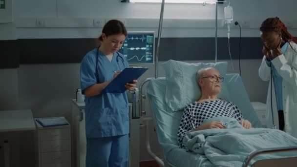 Personel medyczny doradzający choremu pacjentowi na oddziale szpitalnym — Wideo stockowe