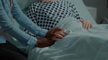 Afro-Amerikalı kadın hastane koğuşundaki hasta hastayı ziyaret ediyor.