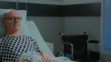 Hastane koğuşunda nazal oksijen tüplü yaşlı bir adamın portresi.