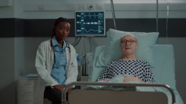 Afro-Amerikalı doktor ve hasta hasta hasta hastane koğuşunda konuşuyor.