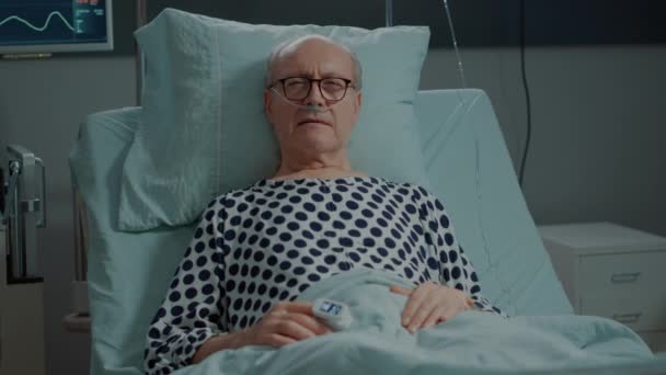 Больной старый пациент на больничной койке с носовой кислородной трубкой — стоковое видео