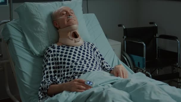 Пациент пожилого возраста, сидящий в палате больницы с шейным воротником — стоковое видео