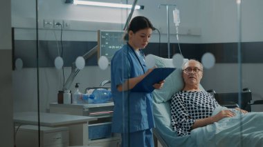 Kafkas hemşire hastane koğuşundaki yaşlı hastayı kontrol ediyor.