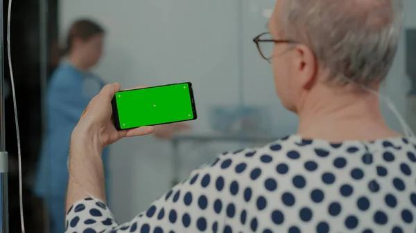 Vecchio malato che tiene il dispositivo dello schermo verde alla struttura — Foto Stock