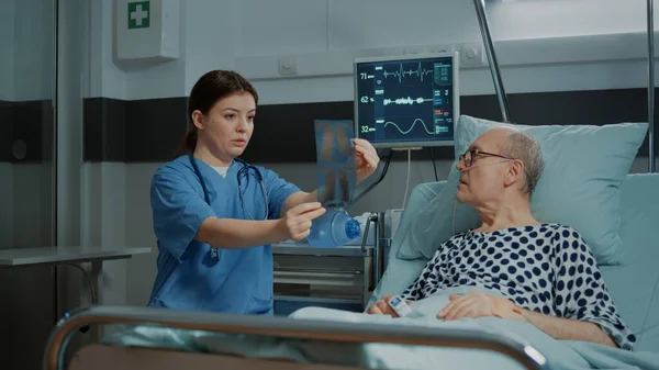 Krankenschwester erklärt Patientin auf Krankenhausstation Röntgentestergebnisse — Stockfoto