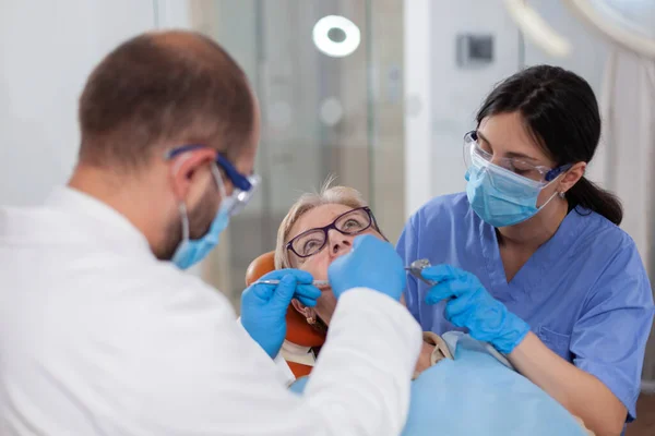 Медсестра помогает стоматологу во время лечения зубов — стоковое фото