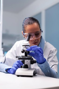 Tıbbi mikroskop kullanarak bakteriyoloji enfeksiyon laboratuvar testini inceleyen uzman bir eczacı.