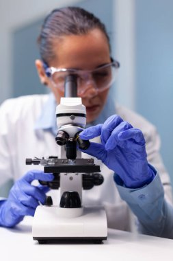 Koronavirüs test sonuçlarını tıbbi mikroskop kullanarak analiz eden bilim kadını doktor.