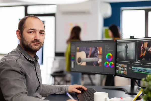 Videographer looking at camera smiling working in creative startup workplace — Stock Photo, Image