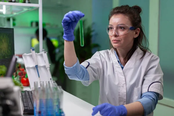 Kimyager genetik olarak modifiye edilmiş sıvıyla test tüpüne bakıyor. — Stok fotoğraf