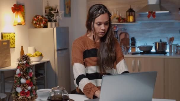 Biała kobieta siedzi przy kuchennym stole z laptopem — Wideo stockowe