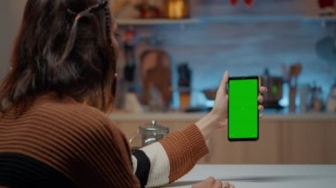 Beyaz kadın elinde yeşil ekranlı akıllı telefon tutuyor.