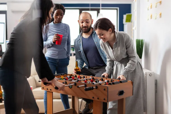 Multi ethnic group of people playing at foosball table
