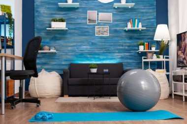 Boş oturma odası. Yoga minderli ve dambıllı fitness antrenmanına hazır kimse yok.