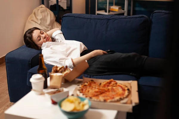 Mujer caucásica durmiendo después de comer comida chatarra en la sala de estar tarde en la noche — Foto de Stock