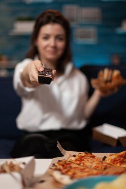 Kanal değiştiren bir kadın televizyonda online film dizisi izliyor.