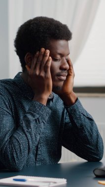 Büyük baş ağrısı olan, migrenden muzdarip, şakaklarını ovuşturan Afrikalı Amerikalı bir adam.