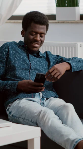 Afrikai amerikai férfi telefonnal a kezében nézi az online streaming szolgáltatások tartalmát — Stock Fotó