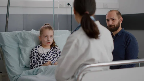 Lekarz pediatra omawiający leczenie choroby z chorym pacjentem i ojcem — Zdjęcie stockowe