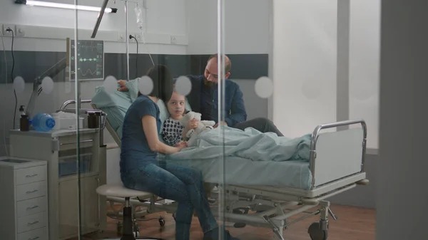 Bezorgde ouders zitten met ziek meisje dochter wachten op ziekte expertise tijdens medisch onderzoek — Stockfoto