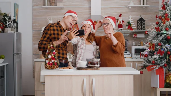 Família tirando selfie usando smartphone desfrutando de férias de inverno em xmas cozinha decorada — Fotografia de Stock
