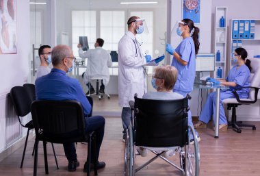 Koruma maskesi takan hemşire ve uzman doktor resepsiyon odasında konuşuyor.