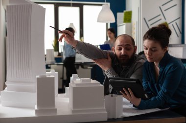 İnşaat mimarlarından oluşan bir ekip ofiste tablet üzerinde çalışıyor.