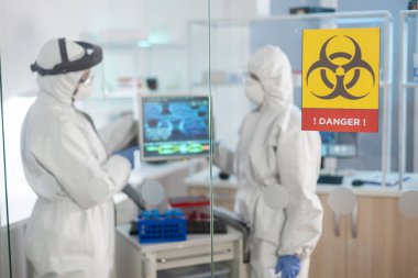 Tıp laboratuarında tehlike işareti ve bilim adamı çalışıyor.