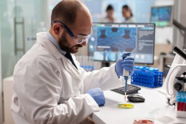 Bilim adamı kan örneğini mikropipetle petri kabına bırakıyor.
