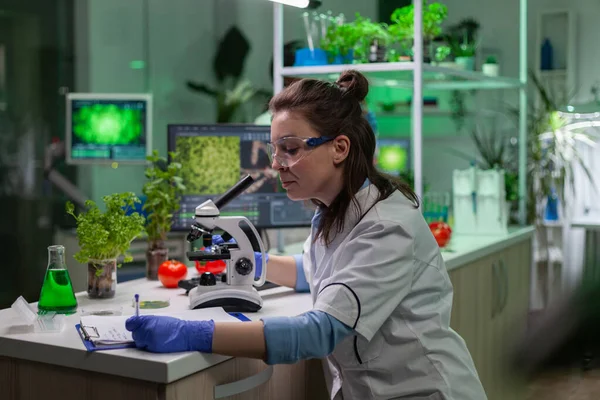 Biologist scientist looking at leaf sample using medical microscope — Stock Photo, Image