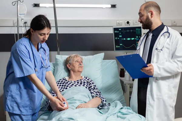 Zdravotní sestra vázání oxymetr na starší ženy pacienta — Stock fotografie