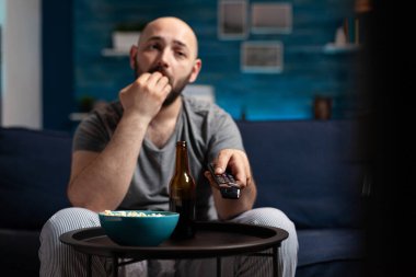 Korkmuş adam TV 'de korku filmi seyrediyor, patlamış mısır yiyor.