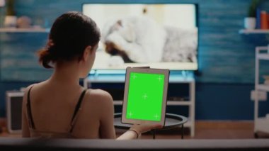 Beyaz kadın dijital tablette dikey olarak yeşil ekran tutuyor