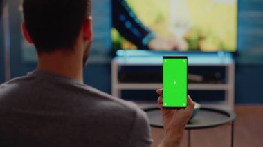 Modern akıllı telefonlu biri yeşil ekrana bakıyor.