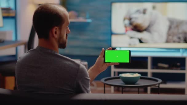 Młody człowiek ogląda poziomy zielony ekran na smartfonie — Wideo stockowe