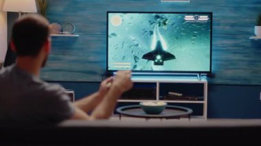 Oyun konsolunda oyun oynayan adam joystick kullanıyor