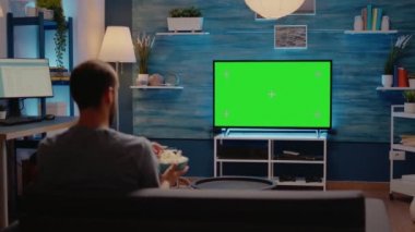 Beyaz adam yeşil ekran televizyona bakıyor.