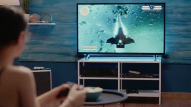 Konsolda aksiyon oyunu oynayan genç bir kadın