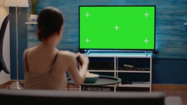 Televizyonda yeşil ekranda denetleyici kullanan genç bir kadın.