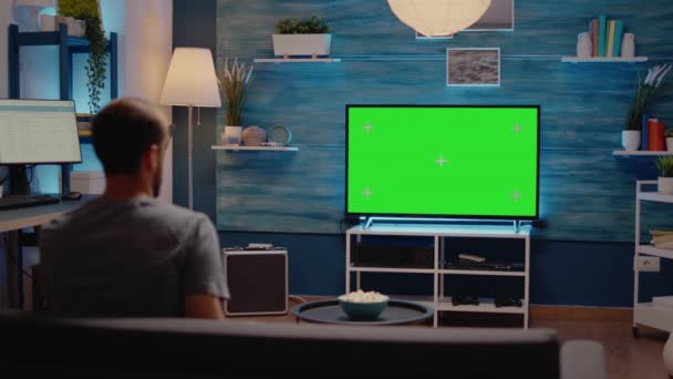 Mężczyzna ogląda telewizję z zielonym ekranem wyświetlacz — Wideo stockowe