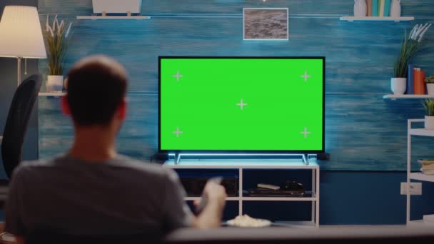 Hombre usando control remoto de TV en fondo de pantalla verde — Vídeos de Stock