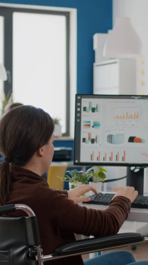 Felç olmuş finansal uzman tekerlekli sandalyede oturmuş ekonomi istatistiklerini analiz ediyor.