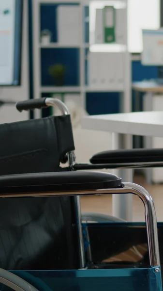 Rollstuhl in leerem Büroraum neben Schreibtisch in Start-up-Firma abgestellt — Stockfoto
