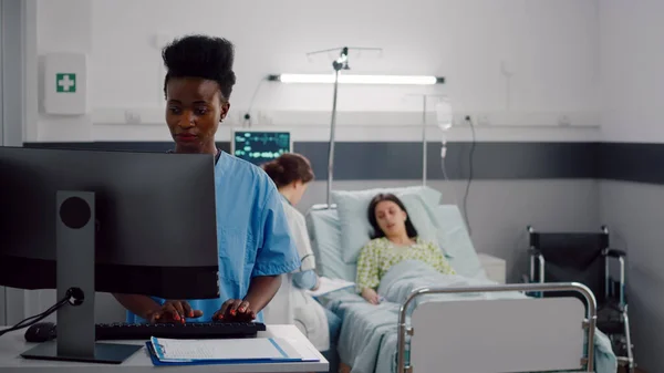 Assistante noire tapant le traitement de soins de santé sur ordinateur — Photo
