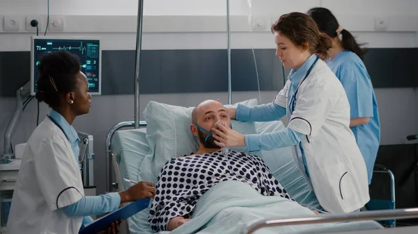 Medical team monitoring heartbeat pulse of sick man during respiratory emergency — Stock Photo, Image