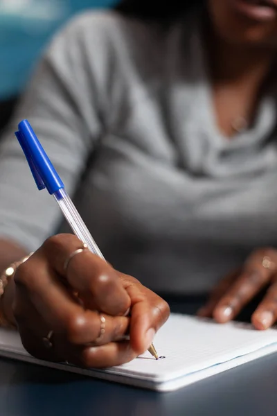 Close-up van de student met donkere huid schrijven universitair huiswerk op notebook — Stockfoto