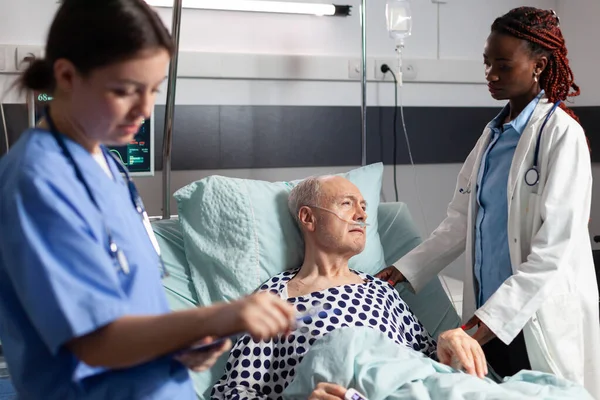 Afrikanischer Arzt im Krankenhauszimmer diskutiert mit krankem Senior — Stockfoto