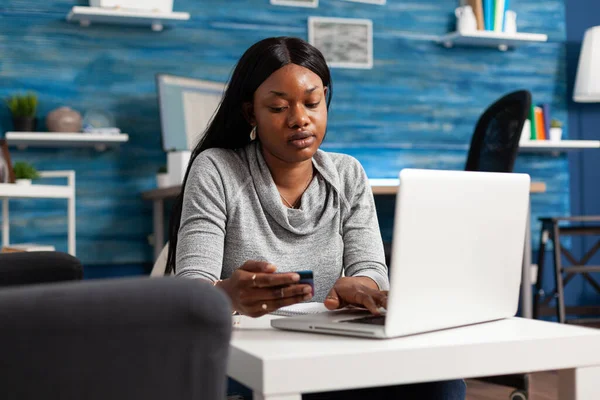 Étudiant afro-américain assis sur un sac de haricots dans le salon tenant une carte de crédit — Photo