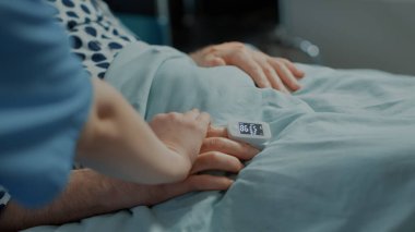 Yaşlı hasta hastane koğuşundaki hemşireden yardım alıyor.